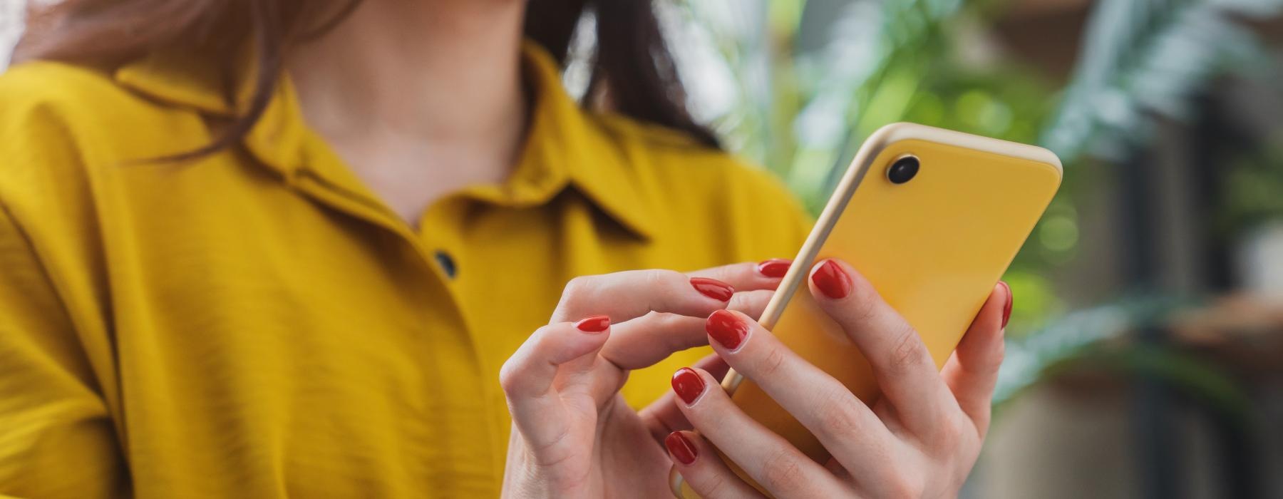 a woman holding a yellow cell phone