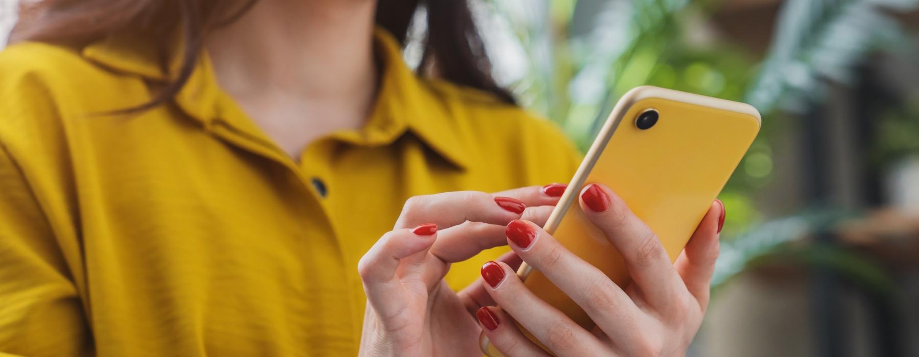 a woman holding a yellow cell phone